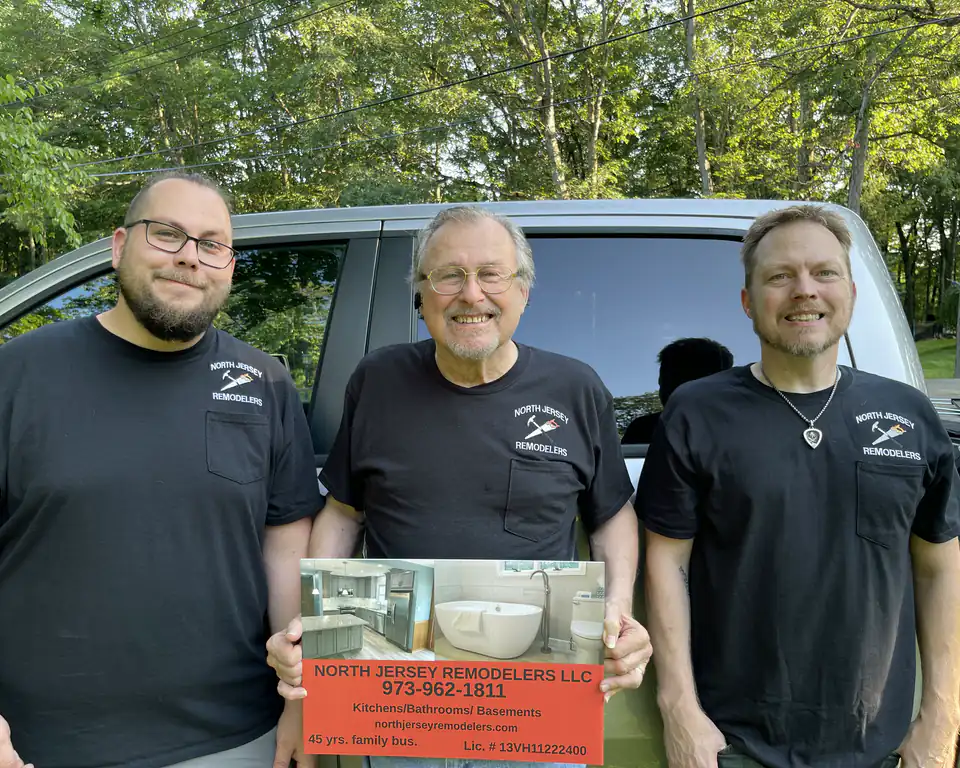 Bob Dion with his sons Rob and Chris, in North Jersey Remodelers shirts, holding the company sign